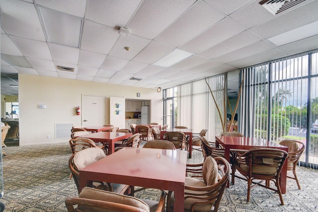 dining space featuring a drop ceiling, a healthy amount of sunlight, and expansive windows