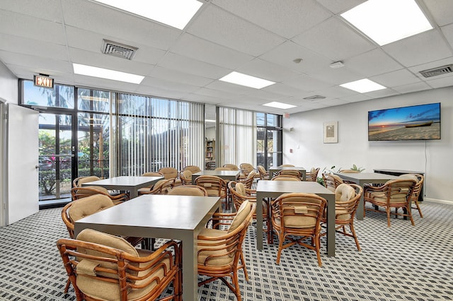 dining area featuring a paneled ceiling, floor to ceiling windows, and carpet