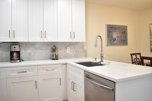 kitchen featuring tasteful backsplash, dishwasher, a peninsula, white cabinetry, and a sink