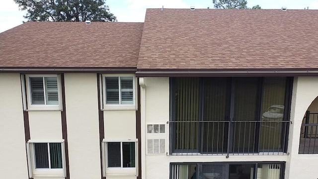 view of side of property with a shingled roof and stucco siding