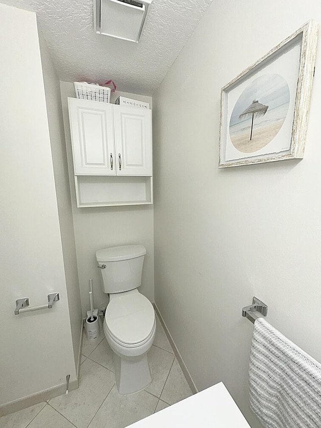 bathroom featuring a textured ceiling, tile patterned flooring, toilet, and baseboards