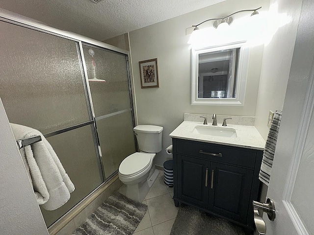 bathroom with toilet, a shower stall, a textured ceiling, and vanity