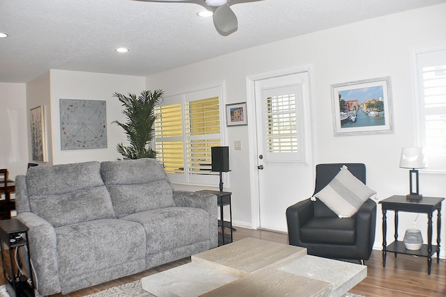 living room with a textured ceiling, ceiling fan, wood finished floors, and baseboards