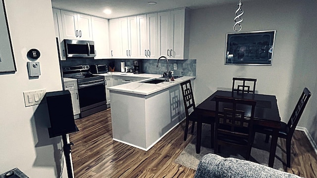 kitchen featuring a sink, white cabinetry, light countertops, appliances with stainless steel finishes, and dark wood finished floors