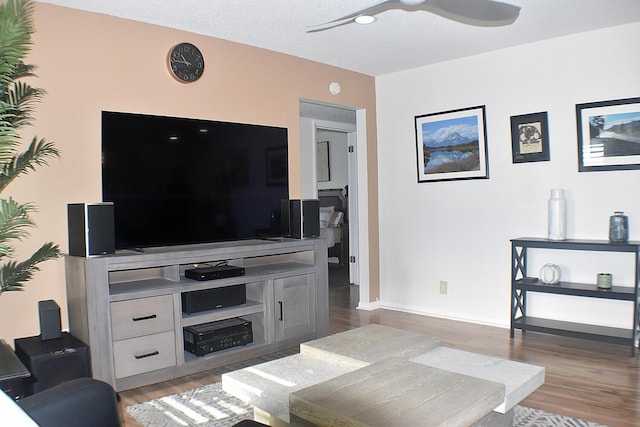 living area featuring light wood-type flooring, a ceiling fan, and baseboards