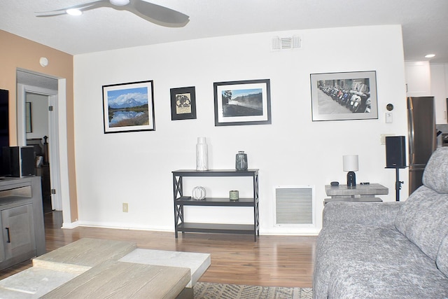 living area featuring baseboards, ceiling fan, visible vents, and wood finished floors