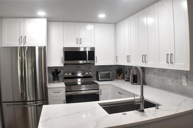 kitchen with appliances with stainless steel finishes, white cabinets, and decorative backsplash