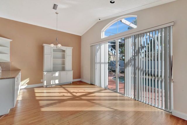 doorway to outside with light wood-type flooring, lofted ceiling, a wealth of natural light, and a chandelier