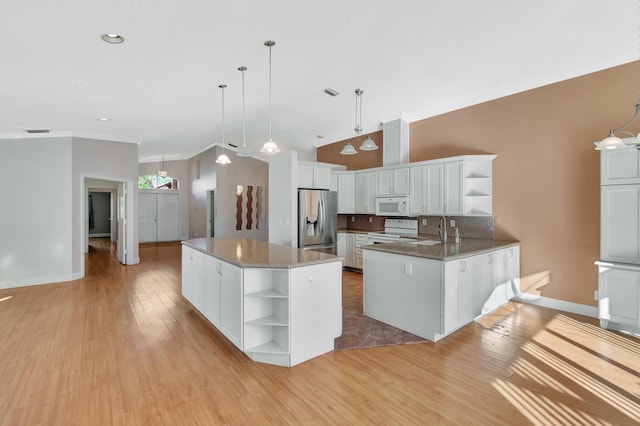 kitchen with tasteful backsplash, white appliances, a kitchen island with sink, decorative light fixtures, and white cabinets