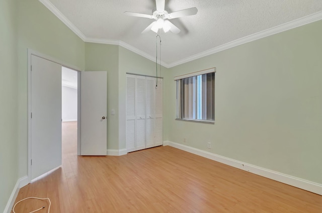 unfurnished bedroom featuring ceiling fan, a textured ceiling, vaulted ceiling, a closet, and ornamental molding