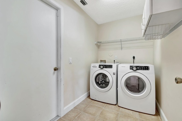 clothes washing area with a textured ceiling and washing machine and clothes dryer