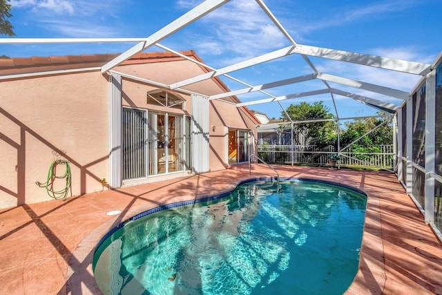 view of swimming pool featuring glass enclosure and a patio