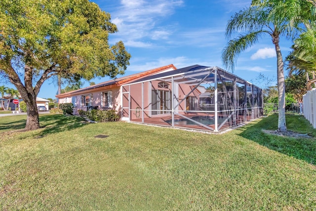 back of house featuring a lanai and a lawn