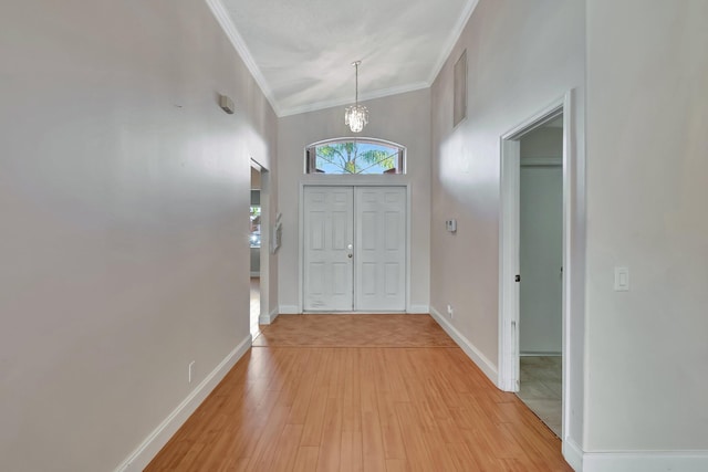 foyer featuring ornamental molding, light hardwood / wood-style floors, and a notable chandelier