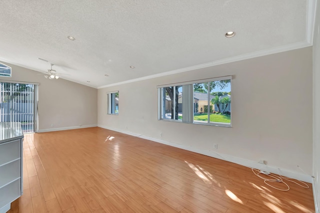 unfurnished room featuring light wood-type flooring, ornamental molding, a textured ceiling, ceiling fan, and lofted ceiling