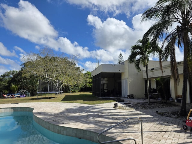 pool with a patio area, a yard, and a trampoline