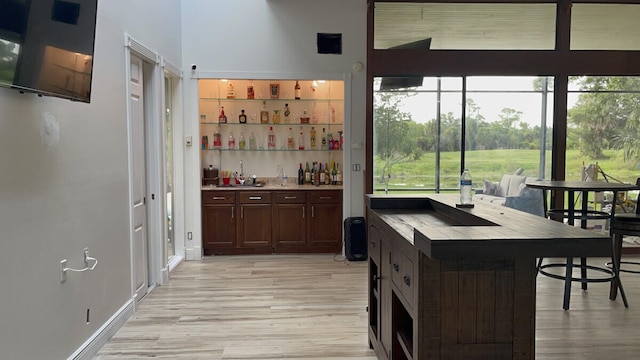 bar with a sink, indoor wet bar, and light wood-style floors