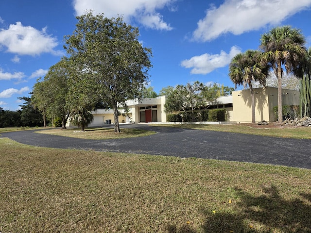 view of front of home with stucco siding, a front lawn, and aphalt driveway