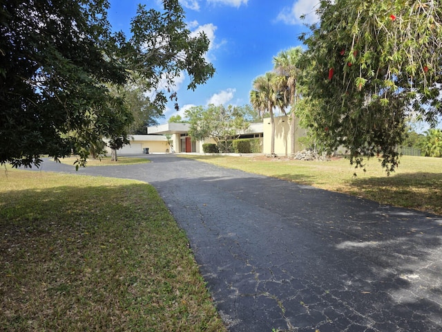 view of front of house featuring aphalt driveway, stucco siding, and a front yard