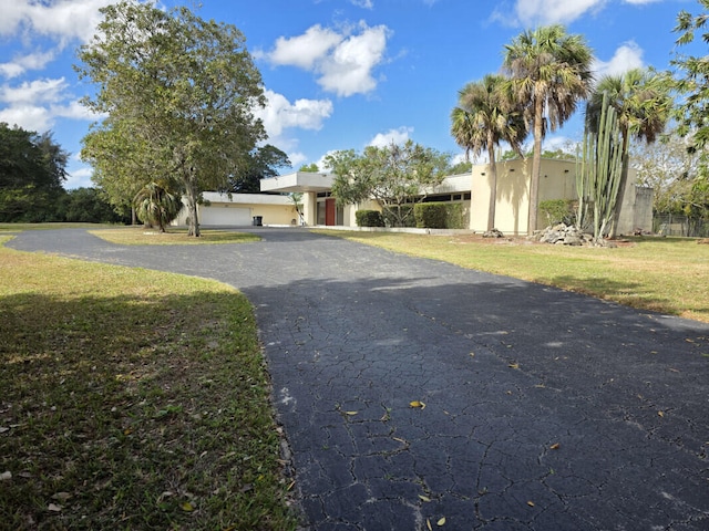 view of front of home featuring stucco siding, driveway, and a front yard