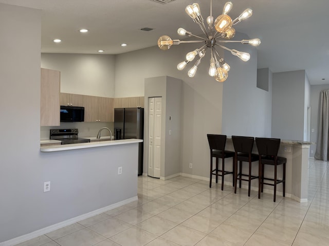 kitchen with light brown cabinets, an inviting chandelier, kitchen peninsula, a breakfast bar, and appliances with stainless steel finishes