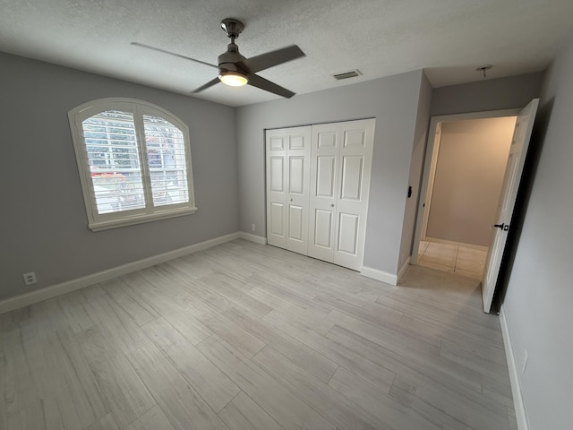 unfurnished bedroom with a textured ceiling, light hardwood / wood-style floors, a closet, and ceiling fan