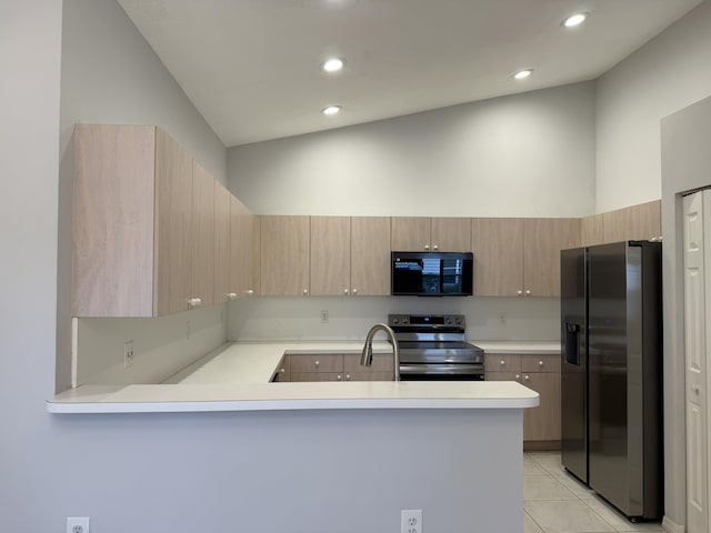 kitchen featuring light tile patterned floors, lofted ceiling, kitchen peninsula, and appliances with stainless steel finishes