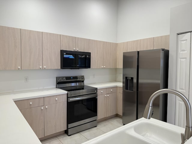 kitchen featuring appliances with stainless steel finishes, sink, light brown cabinetry, and light tile patterned flooring