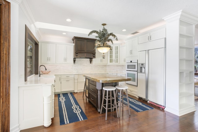 kitchen with sink, white cabinets, paneled refrigerator, and a kitchen island