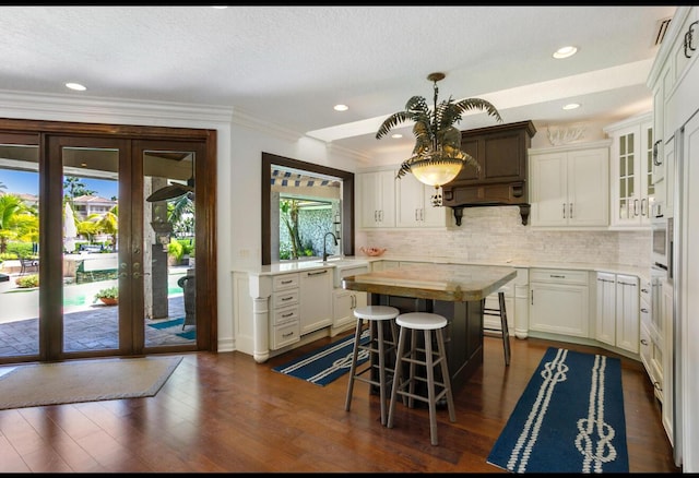 kitchen featuring tasteful backsplash, glass insert cabinets, a sink, dark wood-style floors, and french doors