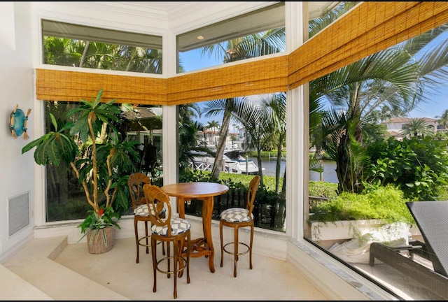sunroom featuring visible vents, plenty of natural light, and a water view