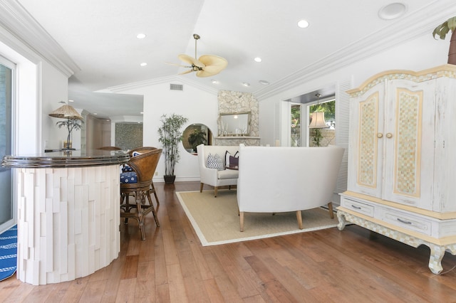 living room with hardwood / wood-style floors, ceiling fan, crown molding, and vaulted ceiling