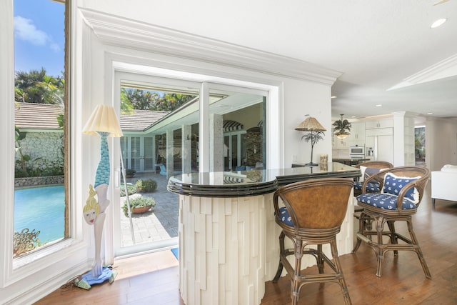 bar featuring ornamental molding, recessed lighting, wood finished floors, and plenty of natural light