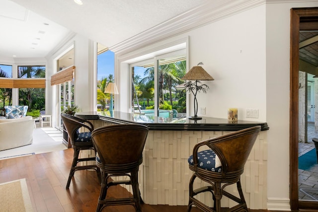 bar with crown molding and wood-type flooring