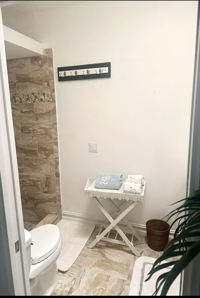 bathroom with baseboards, a stall shower, toilet, and marble finish floor