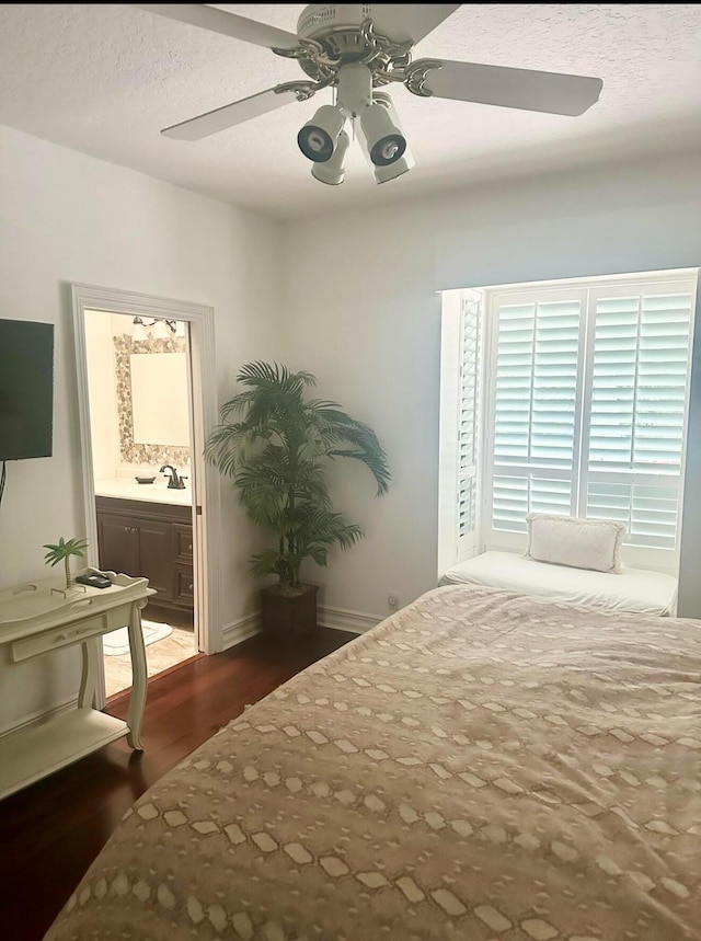 bedroom with sink, dark hardwood / wood-style flooring, ceiling fan, and connected bathroom