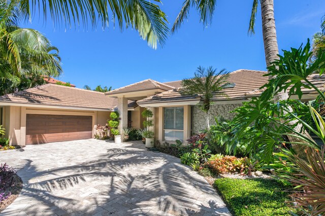 view of front of house featuring an attached garage, a tile roof, decorative driveway, and stucco siding