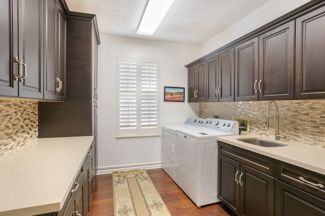 clothes washing area with sink, cabinets, dark wood-type flooring, separate washer and dryer, and a textured ceiling