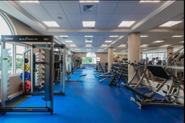 exercise room with a wealth of natural light, a drop ceiling, and visible vents