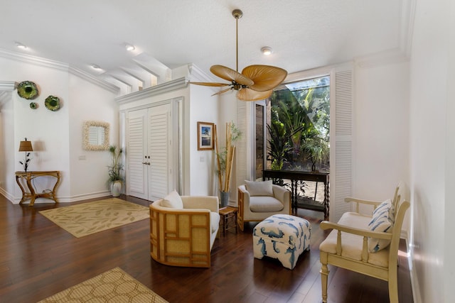 living area featuring ceiling fan, dark hardwood / wood-style flooring, crown molding, and a textured ceiling