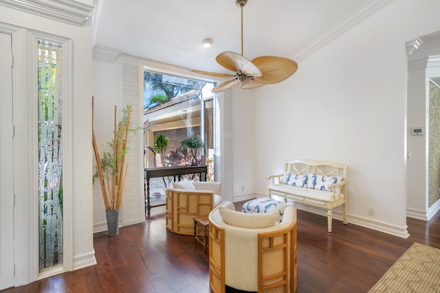 living area featuring ceiling fan, dark hardwood / wood-style flooring, ornamental molding, and a textured ceiling