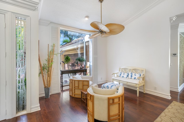 sitting room with wood finished floors, a ceiling fan, and ornamental molding