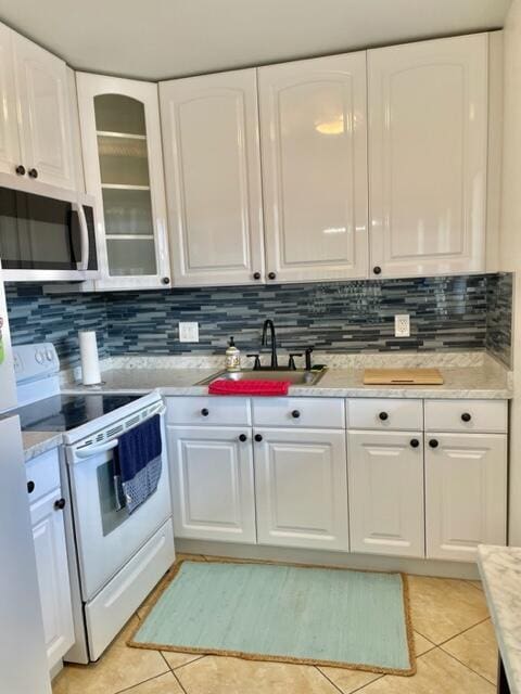 kitchen with white electric range, light tile patterned floors, white cabinetry, and sink