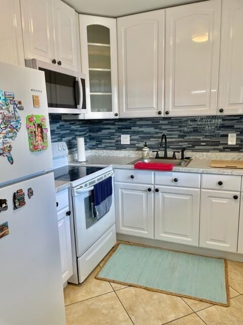 kitchen with light tile patterned floors, white appliances, white cabinetry, and sink