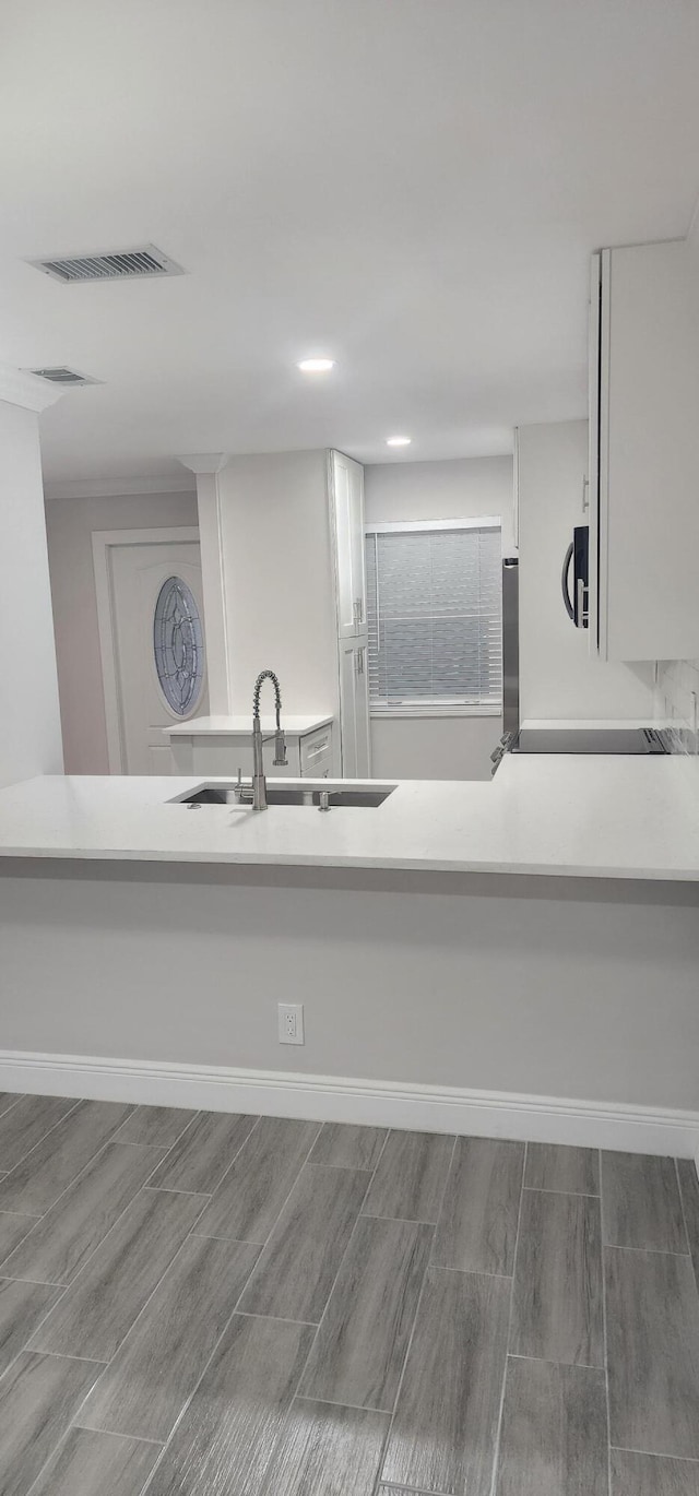 kitchen with white cabinets, wood-type flooring, and sink