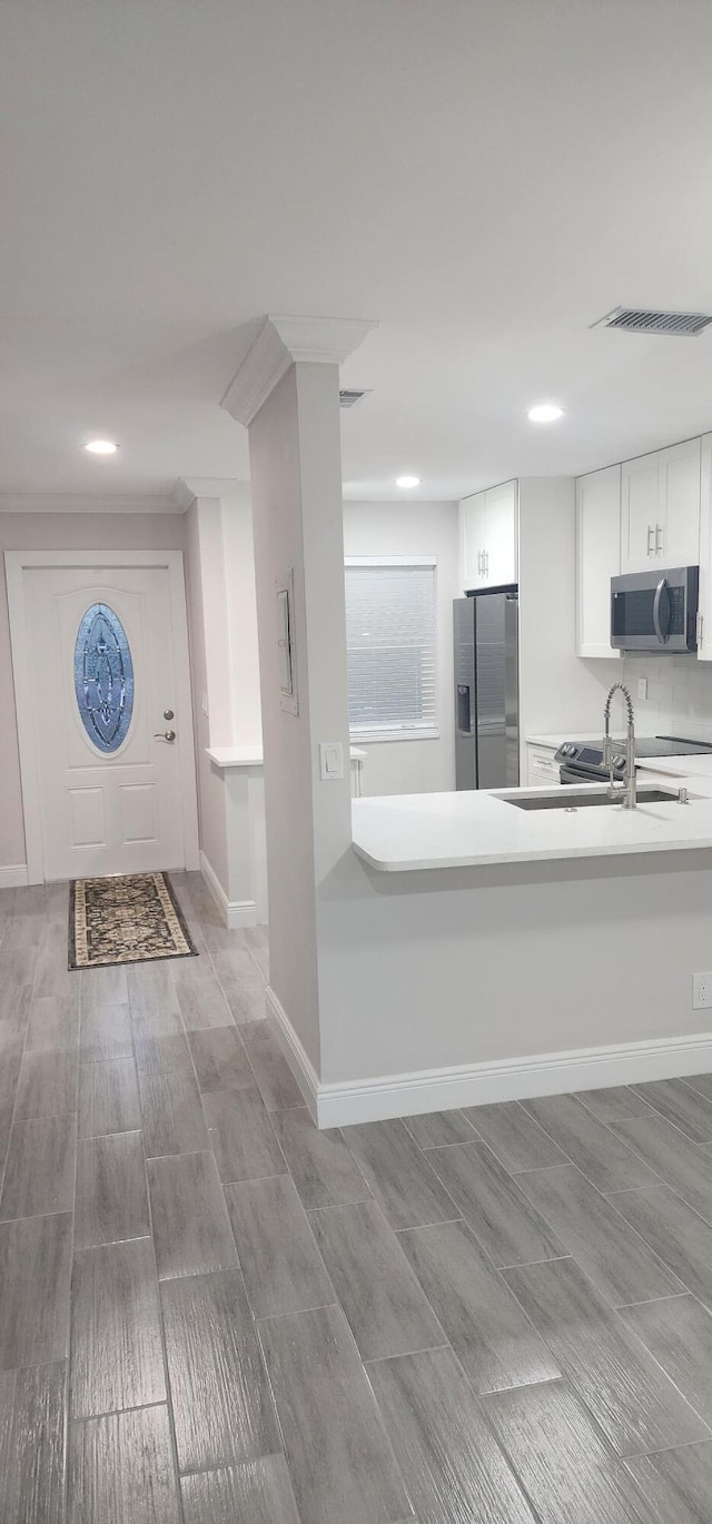 kitchen featuring appliances with stainless steel finishes, light wood-type flooring, white cabinetry, and sink