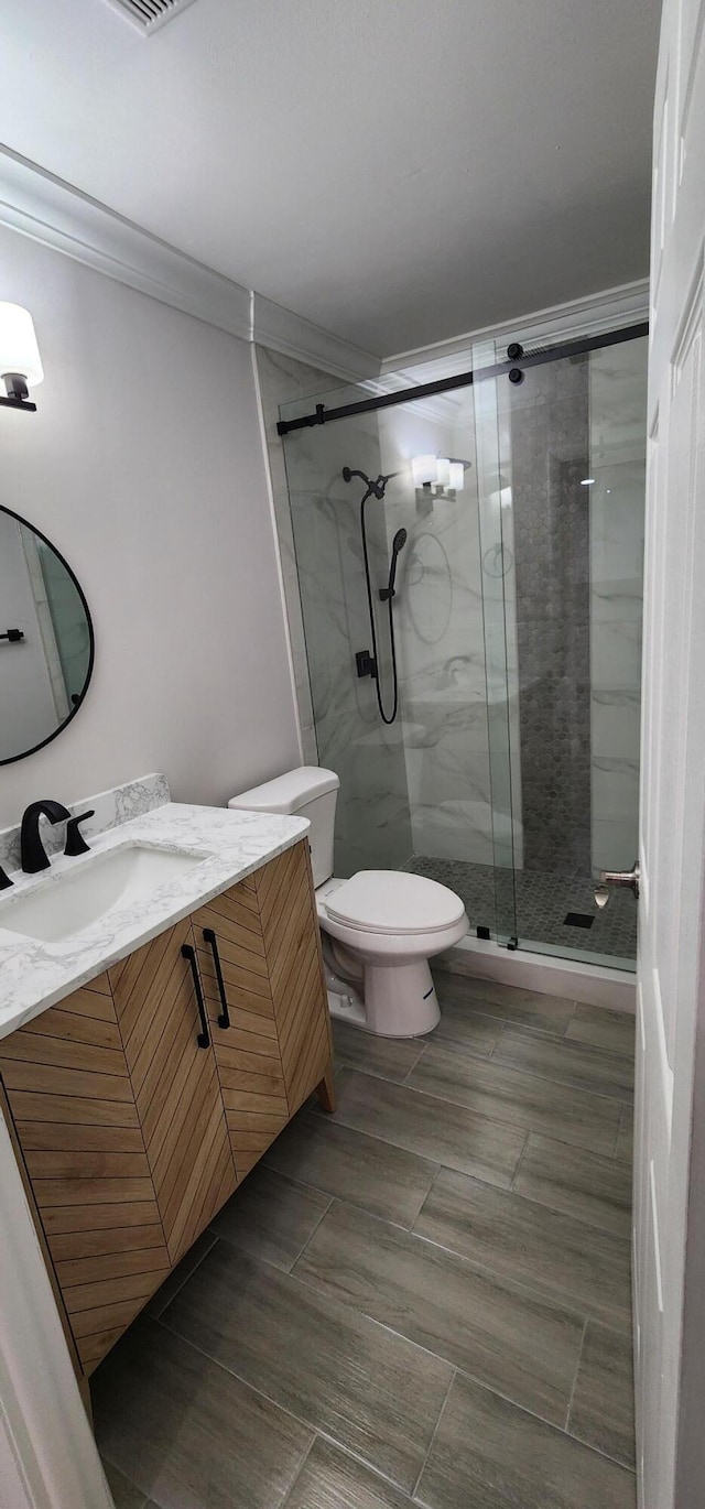 bathroom featuring vanity, toilet, an enclosed shower, and ornamental molding