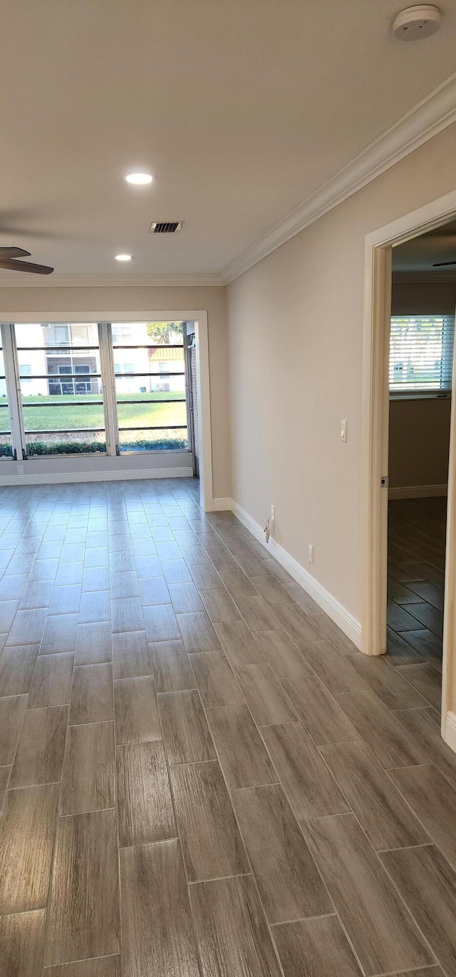 empty room with hardwood / wood-style flooring, ceiling fan, crown molding, and a wealth of natural light