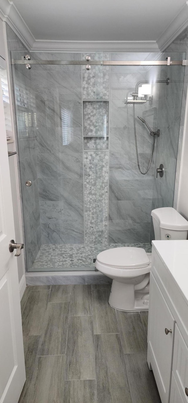 bathroom with crown molding, vanity, a shower with shower door, and toilet