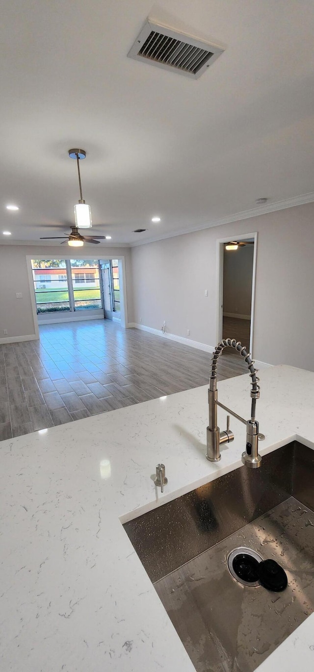 interior space with hardwood / wood-style floors, ceiling fan, crown molding, and sink